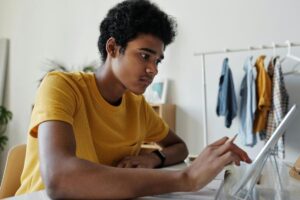 Youth reading on a tablet holding a pencil.